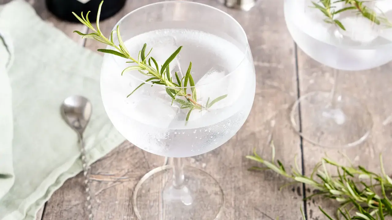 Erfrischender Gin Tonic mit Rosmarin und Eis. Ein Hauch von Kräutern für den perfekten Genuss.