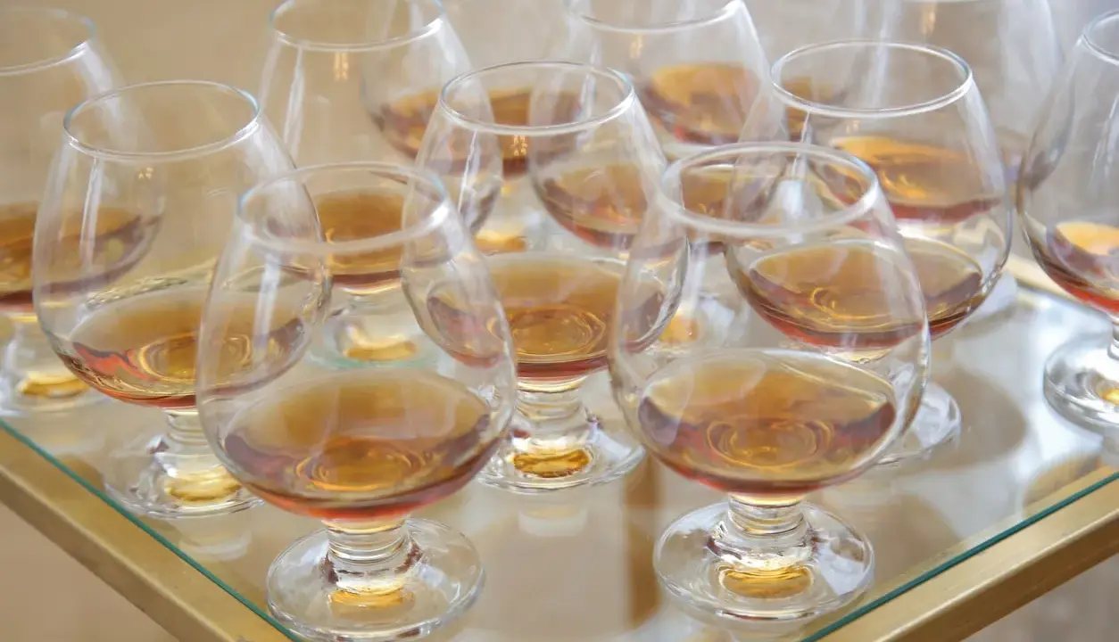 Viele Gläser mit bernsteinfarbenem Metaxa stehen bereit. Was ist Metaxa? Ein griechischer Weinbrand, der nach einer geheimen Rezeptur hergestellt wird.