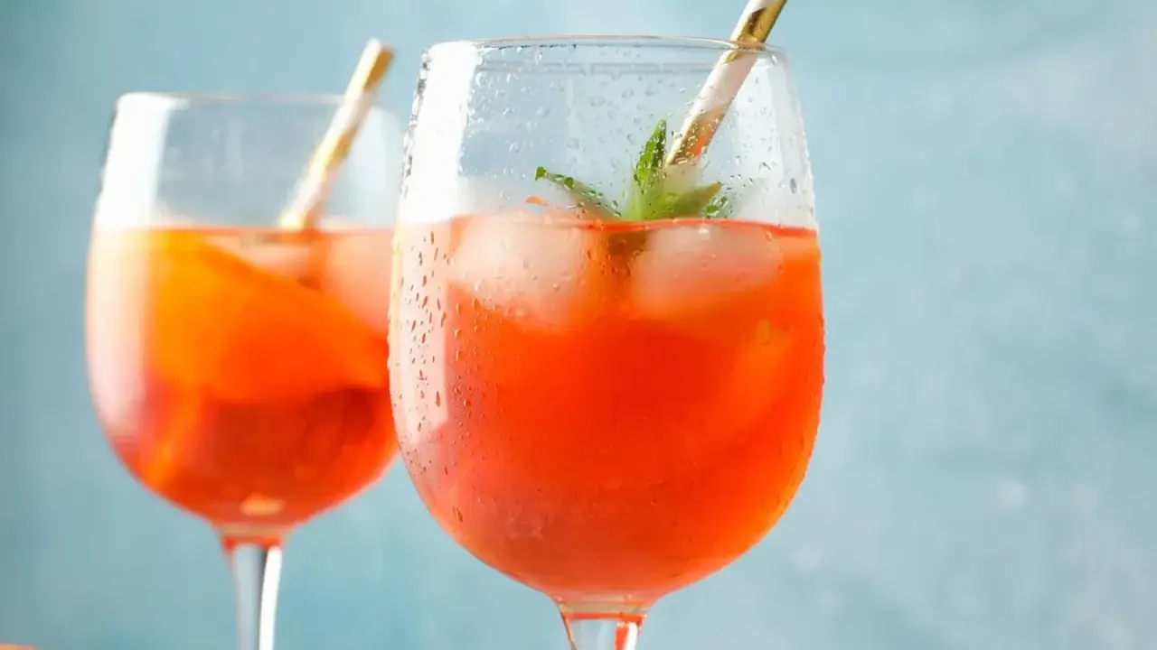 Erfrischendes Aperol Spritz Rezept: Zwei Gläser mit Eis, Orange und Minze, bereit zum Genießen.