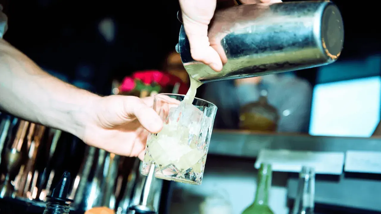 Barkeeper gießt erfrischendes bitter lemon tonic water mit Eis in ein Glas.
