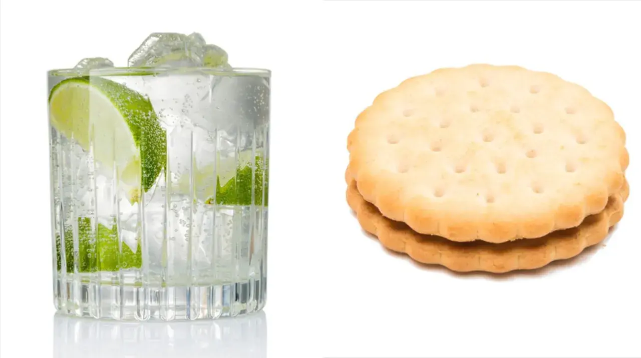 Erfrischender Gin Tonic mit Limette und Eis, daneben zwei Kekse. Denken Sie an die Gin Tonic Kalorien!