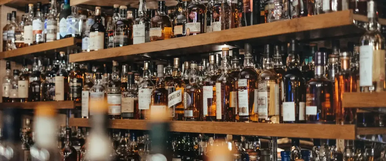 Regale voller Flaschen mit goldbraunem Whisky oder Whiskey. Eine Auswahl für Kenner.