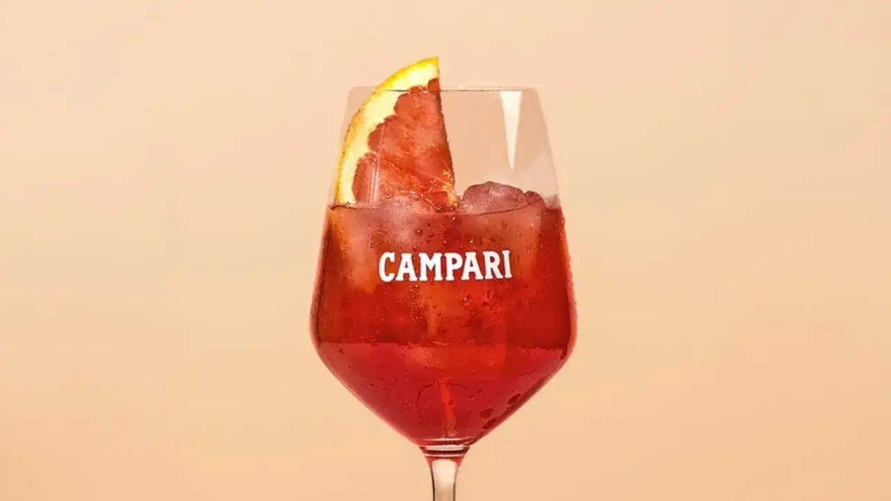 Ein erfrischender Campari Cocktail mit Eis und einer Orangenscheibe, perfekt für einen warmen Abend.