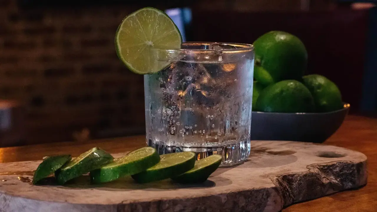 Erfrischender Gin Tonic mit Eis, Limettenscheiben und einer Schale voller Limetten. Perfekt für einen warmen Abend.
