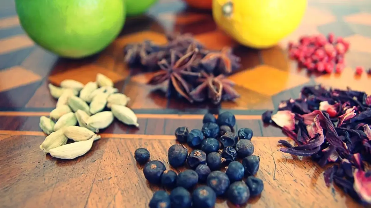 Vielfalt an **Gin Zutaten**: Wacholderbeeren, Kardamom, Sternanis, Hibiskus und Zitrusfrüchte auf einem Holztisch.