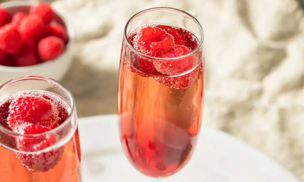 Zwei Gläser Kir Royal mit frischen Himbeeren. Ein einfaches Kir Royal Rezept für besondere Momente.