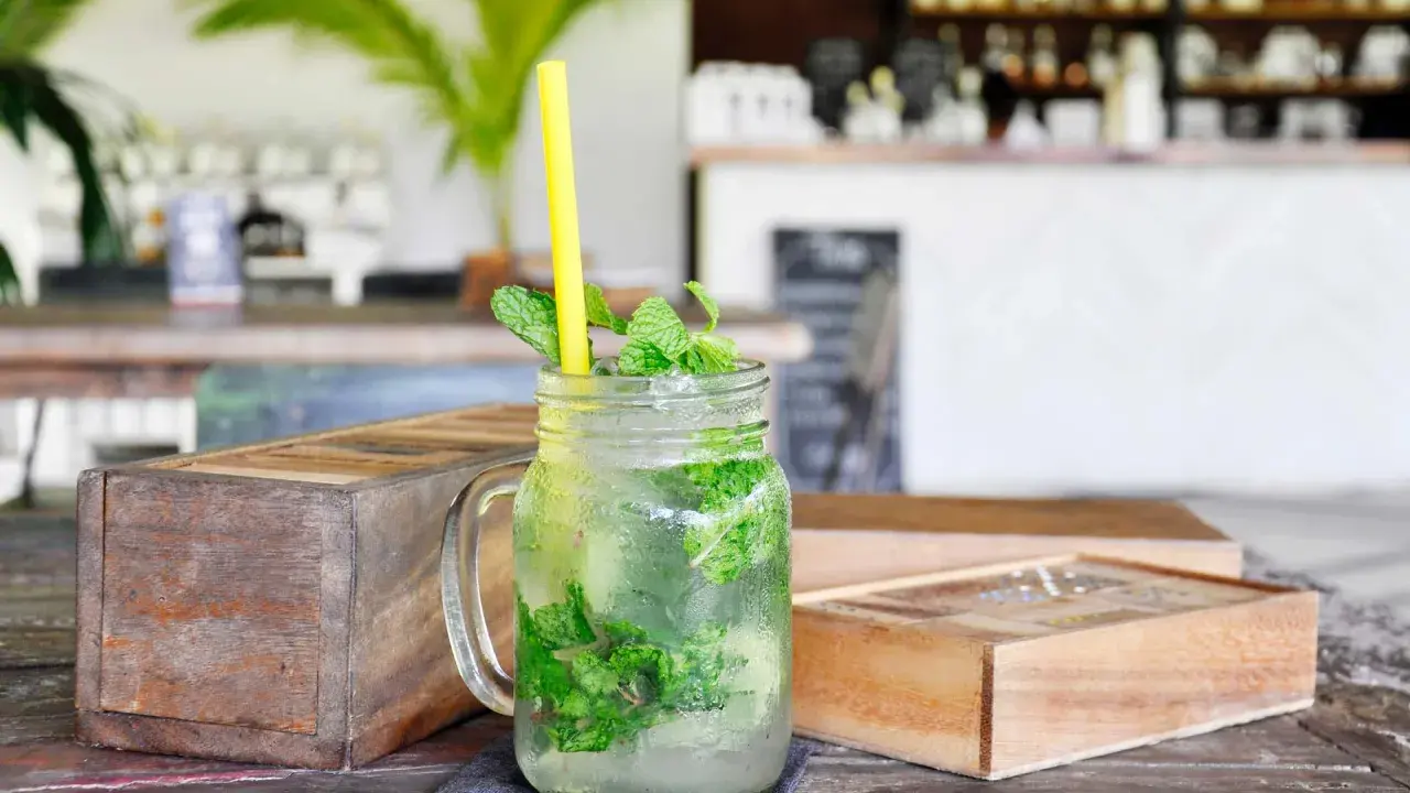 Erfrischender Mojito mit Minze und Eis in einem Glas, dazu ein gelber Strohhalm. Was ist rum? Ein köstlicher Drink!