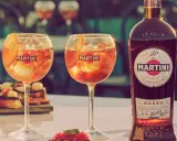 Zwei Gläser Martini mit Eis und Orangenscheibe, daneben eine Flasche Martini Rosso. Perfekt für den Aperitif, mit dem richtigen Martini prozent.