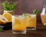 Erfrischender birnen spritz mit Zitrone und Kräutern, serviert mit frischen Früchten und einem Krug des Getränks.