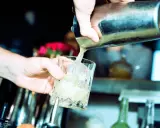 Barkeeper gießt erfrischendes bitter lemon tonic water mit Eis in ein Glas.
