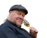 Ein Mann mit Schiebermütze und Bart hält ein Glas bernsteinfarbenen Rum. Er scheint zu wissen, wie man Rum genießt.