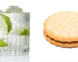 Erfrischender Gin Tonic mit Limette und Eis, daneben zwei Kekse. Denken Sie an die Gin Tonic Kalorien!