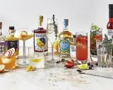 Vielfalt an Getränken und Zutaten für Cocktails, darunter Gin, Likör und Früchte. Perfekt für die Zubereitung eines erfrischenden Gin Tonic Garnitur.