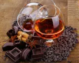 Zwei Cognacgläser, umgeben von Schokolade, Zimt und Sternanis. Die Frage, ob **kann Cognac schlecht werden**, bleibt offen.