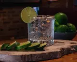 Erfrischendes Glas mit Eis, Limettenscheiben und einer Schale voller Limetten – perfekt für ein Tonic Water Rezept.