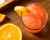 Gefrorene Aperol Spritz Varianten mit frischen Orangenscheiben auf Holztisch.