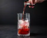 Ein Barkeeper gießt Campari Gin mit Eis in ein Glas.