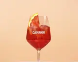Ein erfrischender Campari Cocktail mit Eis und einer Orangenscheibe, perfekt für einen warmen Abend.