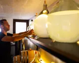 Mann prüft große Glasballons mit Flüssigkeit. Er achtet darauf, dass der Inhalt nicht schlecht wird, wie bei manchem Gin.
