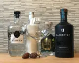 Gin-Flaschen, ein Glas und Zapfen. Der **Wacholder Geschmack** ist bei diesen Gins zentral.