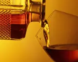 Bernsteinfarbener Armagnac fließt aus einer Karaffe in ein Glas. Was ist das? Ein edler Weinbrand aus Frankreich.