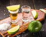 Zwei Gläser Tequila, eines mit Salzrand und Limettenspalte, daneben Salz und Limetten. Perfekt zum Tequila trinken.