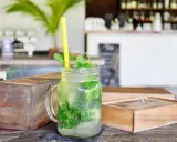 Erfrischender Mojito mit Minze und Eis in einem Glas, dazu ein gelber Strohhalm. Was ist rum? Ein köstlicher Drink!