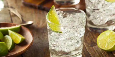 Erfrischender Gin Tonic mit Eis und Limettenspalten. So trinkt man Gin am besten: pur, mit Tonic und frischer Limette.