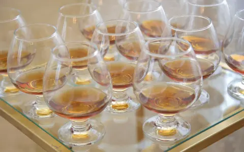 Viele Gläser mit bernsteinfarbenem Metaxa stehen bereit. Was ist Metaxa? Ein griechischer Weinbrand, der nach einer geheimen Rezeptur hergestellt wird.