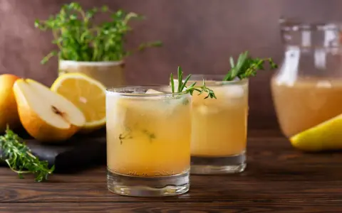 Erfrischender birnen spritz mit Zitrone und Kräutern, serviert mit frischen Früchten und einem Krug des Getränks.