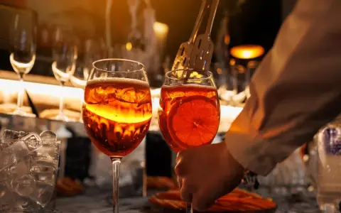 Zwei Aperol Spritz Gläser, bereit zum Genuss. Die leuchtende Farbe erinnert an die Aperol Herkunft in Italien.