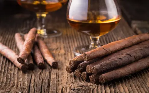 Zwei Gläser Cognac und Zigarren auf Holztisch. So trinkt man Cognac: langsam und genussvoll.