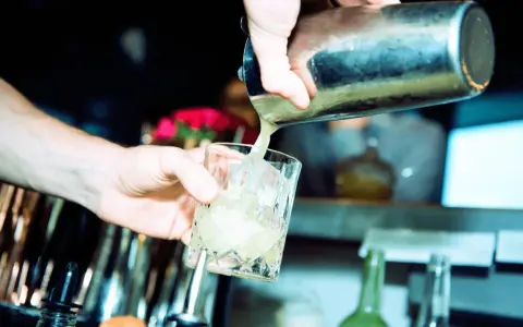 Barkeeper gießt erfrischendes bitter lemon tonic water mit Eis in ein Glas.