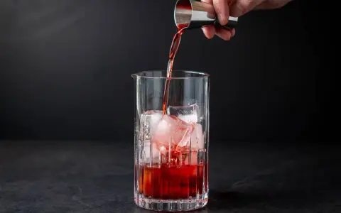 Ein Barkeeper gießt Campari Gin mit Eis in ein Glas.
