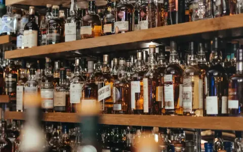 Regale voller Flaschen mit goldbraunem Whisky oder Whiskey. Eine Auswahl für Kenner.