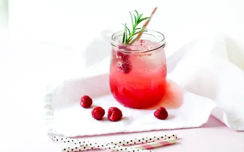 Erfrischender Gin Tonic mit Himbeeren, garniert mit Rosmarin. Ein süßer Genuss an einem warmen Tag.