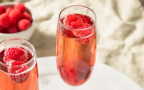 Zwei Gläser Kir Royal mit frischen Himbeeren. Ein einfaches Kir Royal Rezept für besondere Momente.