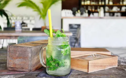 Erfrischender Mojito mit Minze und Eis in einem Glas, dazu ein gelber Strohhalm. Was ist rum? Ein köstlicher Drink!