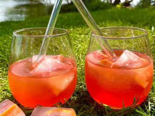 Zwei Gläser Aperol Tonic mit Eis und Orangenscheiben stehen im Gras.