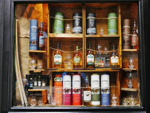 Regale voller Flaschen und Tuben mit irischem Whisky, bereit zum Whisky lagern. Verschiedene Marken wie Tyrconnell und Kilbeggan sind zu sehen.