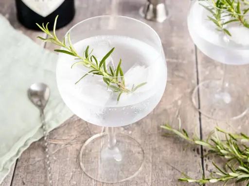 Erfrischender Gin Tonic mit Rosmarin und Eis. Ein Hauch von Kräutern für den perfekten Genuss.