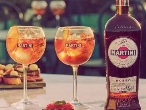 Zwei Gläser Martini mit Eis und Orangenscheibe, daneben eine Flasche Martini Rosso. Perfekt für den Aperitif, mit dem richtigen Martini prozent.