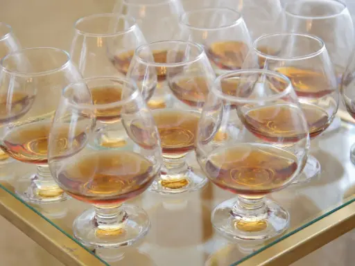 Viele Gläser mit bernsteinfarbenem Metaxa stehen bereit. Was ist Metaxa? Ein griechischer Weinbrand, der nach einer geheimen Rezeptur hergestellt wird.