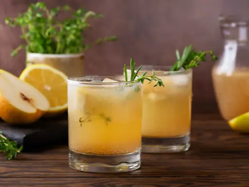 Erfrischender birnen spritz mit Zitrone und Kräutern, serviert mit frischen Früchten und einem Krug des Getränks.
