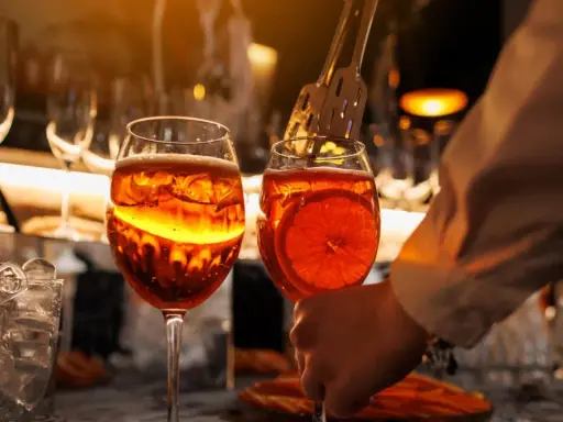 Zwei Aperol Spritz Gläser, bereit zum Genuss. Die leuchtende Farbe erinnert an die Aperol Herkunft in Italien.
