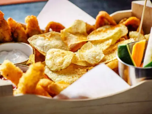 Knusprige Kartoffelchips, frittierte Hähnchenteile und Gemüsesticks – ein perfekter Snack, der gut zu Gin passt.