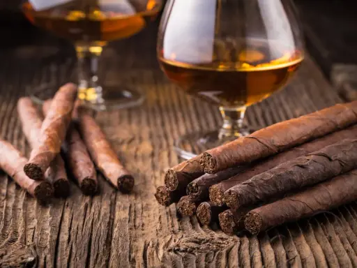 Zwei Gläser Cognac und Zigarren auf Holztisch. So trinkt man Cognac: langsam und genussvoll.