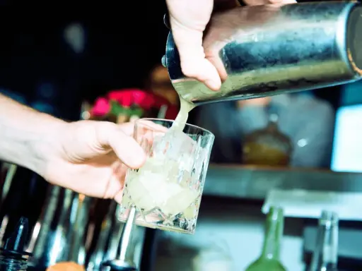 Barkeeper gießt erfrischendes bitter lemon tonic water mit Eis in ein Glas.