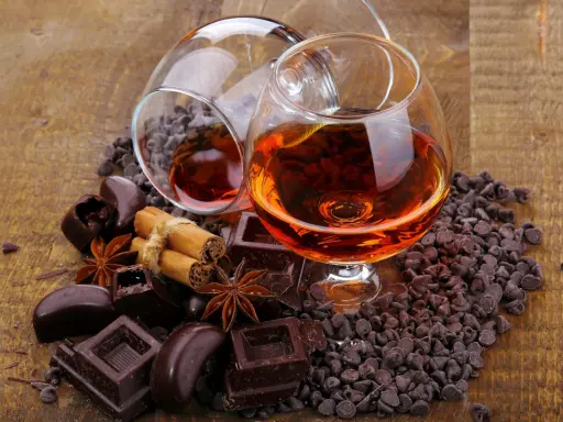 Zwei Cognacgläser, umgeben von Schokolade, Zimt und Sternanis. Die Frage, ob **kann Cognac schlecht werden**, bleibt offen.