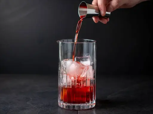Ein Barkeeper gießt Campari Gin mit Eis in ein Glas.